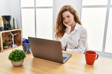 Poster - Young caucasian woman working at the office using computer laptop thinking looking tired and bored with depression problems with crossed arms.