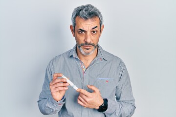 Canvas Print - Handsome middle age man with grey hair holding glucometer device skeptic and nervous, frowning upset because of problem. negative person.