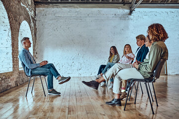 Wall Mural - Young man with a flipboard leading a discussion between a group of people sitting in a circle.