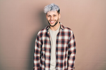 Wall Mural - Young hispanic man with modern dyed hair wearing casual shirt looking positive and happy standing and smiling with a confident smile showing teeth