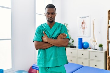 Sticker - Young african physiotherapist man with crossed arms working at pain recovery clinic depressed and worry for distress, crying angry and afraid. sad expression.