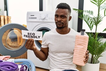 Sticker - Young african man doing laundry holding eco friendly paper skeptic and nervous, frowning upset because of problem. negative person.