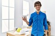 © Krakenimages.com - Young hispanic man using drone at architect office looking positive and happy standing and smiling with a confident smile showing teeth