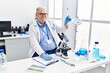 © Krakenimages.com - Middle age grey-haired man wearing scientist uniform holding test tube and writing on clipboard at laboratory