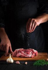 the cook sprinkles the meat with salt. preparing meat before baking. working environment in the kitc