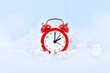 Winter time change for daylight saving in Europe on October 31st concept with red alarm clock between snow