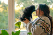 © dinastiya - Happy girl with a puppy. A teenage girl stands near the window with a german spitz puppy
