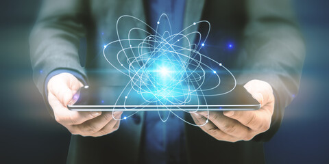 Poster - Close up of businessman hands holding tablet with abstract glowing atom hologram on dark background. Science and connection concept.