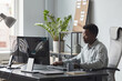 © Seventyfour - Portrait of focused African-American man using computer while sitting at desk in office, software developer concept, copy space