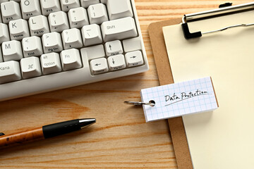Poster - There is  word book with the word of Data Protection. It's on the desk with a clipboard and a keyboard.