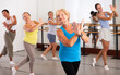 © JackF - Portrait of smiling mature woman practicing ballet dance moves during group class in choreographic studio