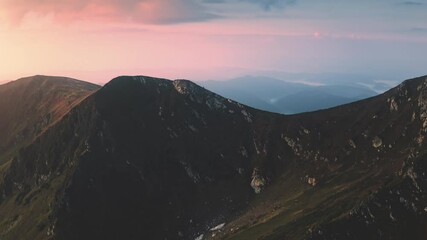 Wall Mural - Mountain peak range summit in pink sunrise. Aerial flight over rocky mount top. Sunset colorful sky. Nature background. Travel destinations. Beautiful wild landscape. Outdoor tourism, summer vacation