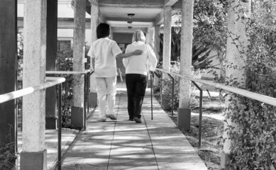 Sticker - Asian doctor helping elderly retired woman with walker stick in the hospital yard. Rehabilitation concept