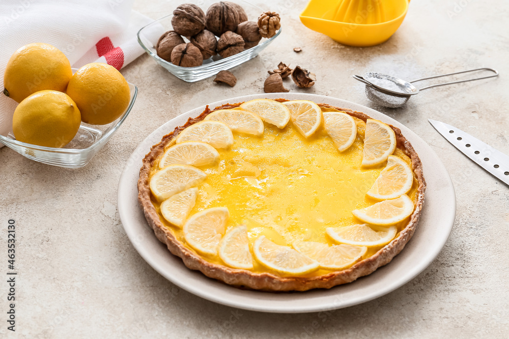 Plate with tasty lemon pie and ingredients on light background