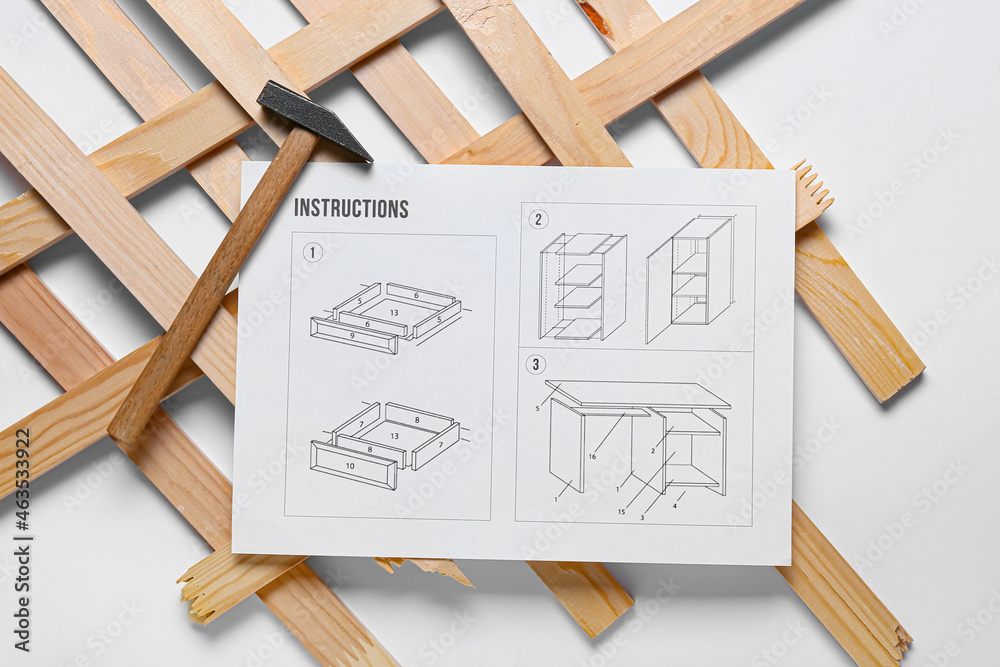 Furniture assembling instructions, hammer and wooden planks on white background