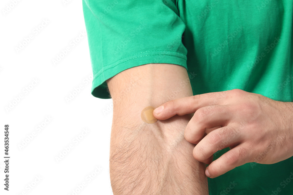 Young man with adhesive patch onto his arm on white background