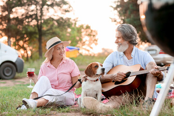 Wall Mural - Happy senior couple with dog at picnic on summer day