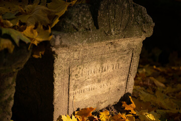 An ancient burial, a gravestone covered with fallen autumn leaves. An old grave. Ancient cemetery