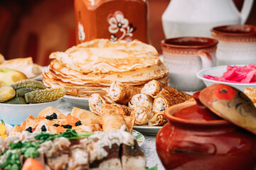 Dishes of the traditional Belarusian cuisine - pancakes, pancakes with caviar, lard, bacon, pickled cucumbers and honey. Attribute of traditional folk celebration of Maslenitsa