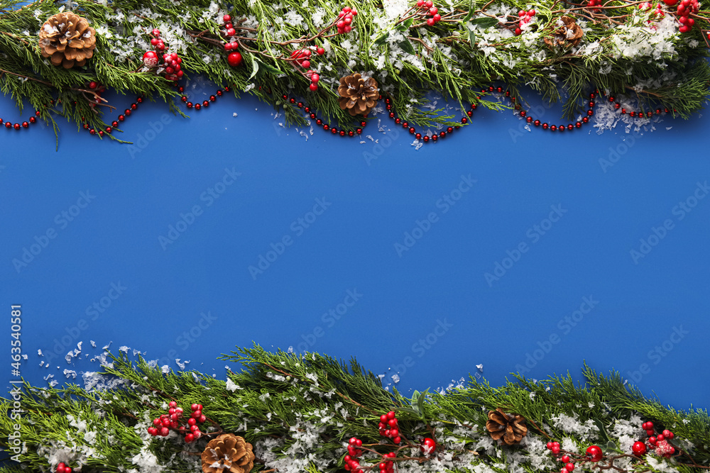 Christmas composition with coniferous branches, decorations and snow on blue background