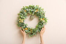 Female Hands With Beautiful Mistletoe Wreath On Color Wall
