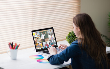 Wall Mural - Caucasian girl using laptop for video call, with smiling diverse elementary school pupils on screen