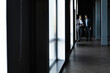 © opolja - Two colleagues communicating in corridor, partners walking in the modern office