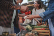© Halfpoint - Close up of woman buying organic vegetables outdoors at local farmers market.