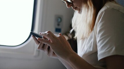 Wall Mural - Train travel woman holding mobile phone texting using 5g device. Close up of hands on a cellphone.