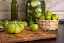 Closeup Of Green Tomatoes On The Wooden Cutting Board And In Basket.Process Of Preparation Of Green Tomatoes Preservation