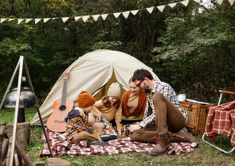 happy smiling family playing chess game at campsite during camping trip in nature