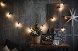 © Svetlana - an element of the design of the New Year's interior in dark color in the loft style with a poster table, a small Christmas tree, light bulbs and decoration