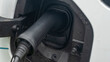 © kalyanby - Close-up view of power supply plugged into an electric car being charged. White electric car charging.