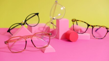 Wall Mural - multiple eyeglasses on a pink ang yellow background, geometric stands, trendy eyeglass frames rolling geometric podiums