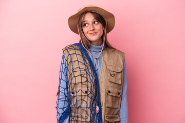 Wall Mural - Young caucasian fisherwoman holding a net isolated on pink background dreaming of achieving goals and purposes