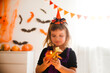 © ulza - happy Child girl in witch costume Halloween with candles, pumpkins and halloween decor. Home festive autumn season holiday decoration.