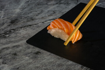 hand picking nigiri with chopstick on marble surface