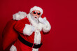 © deagreez - Photo of excited crazy retired man carry big bag gifts wow reaction wear santa hat costume isolated red color background