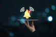 © Dilok - Businessman holding tablet with virtual yellow bell ringing for application notification alert concept.