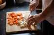 Mężczyzna krojący selera i marchewkę na desce do krojenia w kuchni