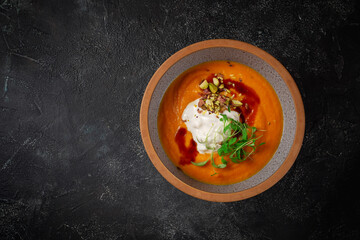 Sticker - Pumpkin cream soup mashed with spices and a sprig of peas on a dark stone table