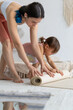 © Вадим Каштанов - Young mother with her little daughter is rolling yoga mat. Yoga Home.