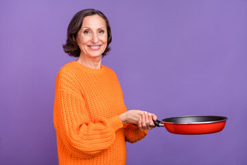 Wall Mural - Profile side photo of lovely mature woman hold frying pan cook delicious breakfast isolated over purple color background