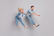 Photo of crazy shocked speechless couple jump wind blow away wear casual jeans outfit isolated grey color background
