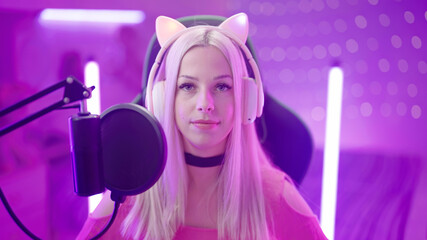 Poster - Portrait of Gamer Girl with cat ear headphones in pink room stare in camera