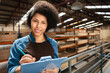 portrait of female worker taking notes on clipboard at storehouse