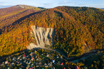 Wall Mural - Aerial view of the huge elephant  rock in carpathian mountains at sunset. Colorful autumn aerial view. Aerial photo of mountains and trees colored into fall colors in small town Yaremche, Ukraine
