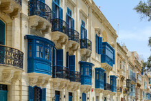 Residential House Facade With Traditional Maltese Navy Blue Enclosed Wooden Balconies In Valletta, Malta, In Summer Day. Authentic Maltese Urban Scene.