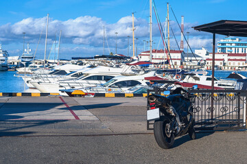 Wall Mural - view from the pier to modern expensive boats and a sports bike in the foreground at the pier of the seaport in the Russian resort town of Sochi