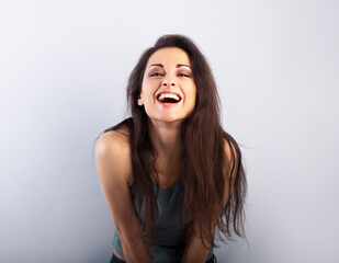 Happy laughing beautiful woman  covering the face the hands on blue background and happy looking in green t-shirt. Portrait